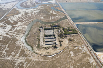 Aerial drone top view of natural sea salt ponds. Farm field outdoor. Material in traditional industry. Salt for industrial use loading in truck by labours.