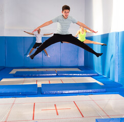 Portrait of teenager boy training jumping movements during workout in indoor trampolines center