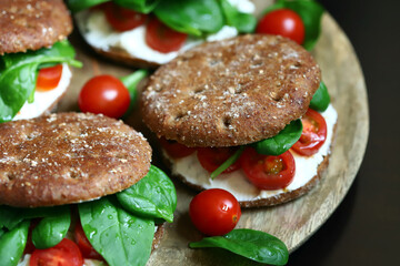 Healthy sandwiches with Philadelphia cheese, spinach and cherry tomatoes with rye buns.