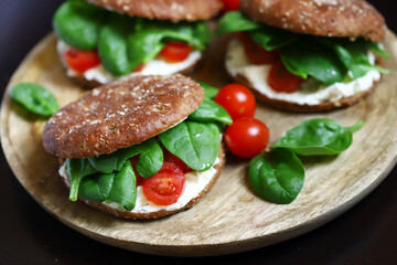 Healthy sandwiches with Philadelphia cheese, spinach and cherry tomatoes with rye buns.