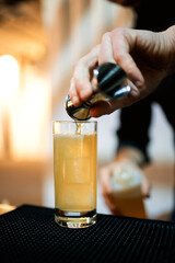 close-up of the bartender's hand pours a cocktail from a glass into a glass