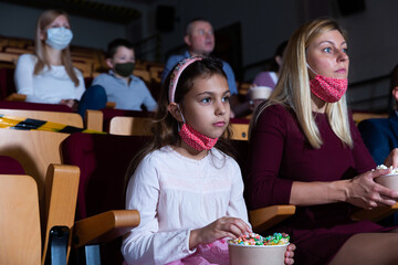 mother, her child sitting at film in auditorium during epidemic