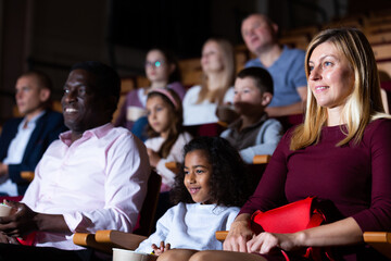 Obraz premium International family enjoys watching comedy in a cinema hall