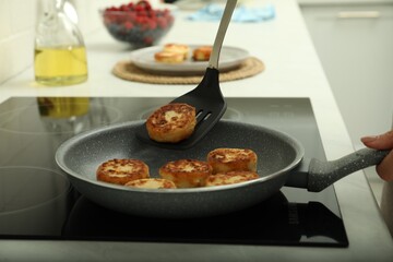 Woman frying delicious cottage cheese pancakes in kitchen, closeup