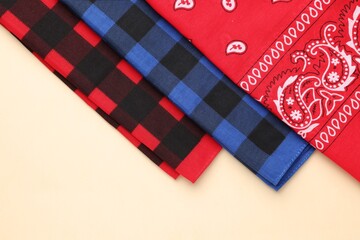 Fototapeta premium Folded bandanas with different patterns on beige background, flat lay