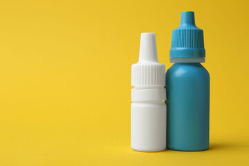 Bottles of medical drops on yellow background. Space for text