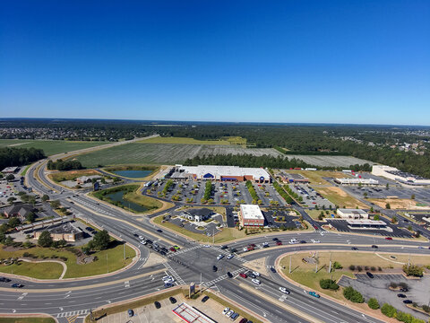 an aerial shot of the city of Warner Robins Georgia with vast miles of lush green trees, grass and plants with buildings and highways with cars driving and a gorgeous clear blue sky 