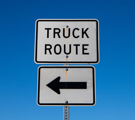 Truck Route Sign with Arrow Pointing Left. Blue Sky in the Background.