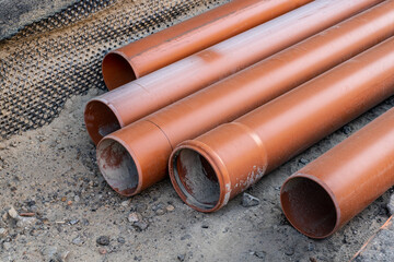 Stack of brown pvc pipes. Close up of orange plastic pipes on construction. Industrial background 