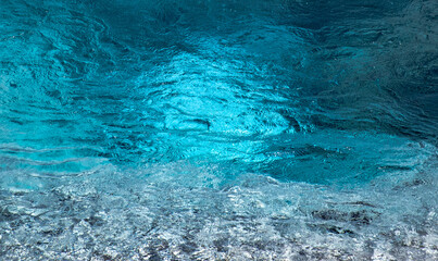Turquoise water surface with a magical light from below. Abstract background.