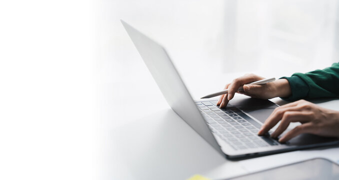 Close-up Businesswoman Working Online On The White Table At Office, Hands Holding Pen And Typing On Laptop Keyboard, Online Job Concept.