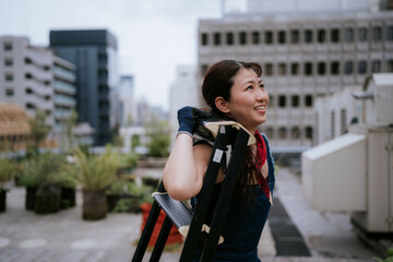 屋外で脚立を運ぶ日本人女性