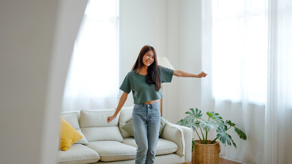 Young asian woman dancing on the floor in living room at home. Happy asia female smile relaxing in...