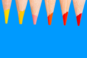 Close Up of six color pencil tips allusive fall season, on blue background with copy space.