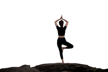 The back of a woman wearing sportswear doing a yoga pose on the rocks.