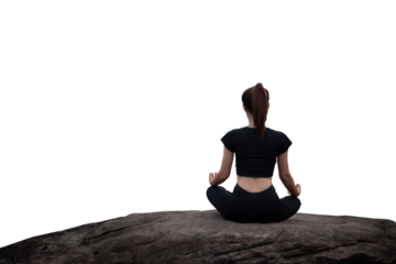 The back of a woman wearing sportswear doing a yoga pose on the rocks.