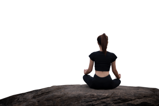 The back of a woman wearing sportswear doing a yoga pose on the rocks.