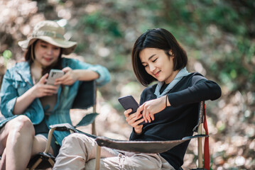 Obraz premium Group of girl friends with smartphone while camping in park
