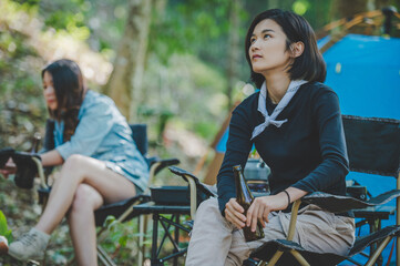 Obraz premium Young women sitting and drink beverage front of camping tent