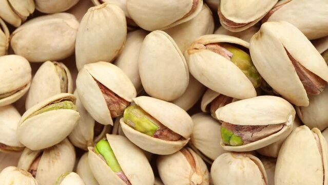 Close up of Pistachios nuts  as a background. raw unsalted pistachios nuts on wooden background. rotating, turning, top view.