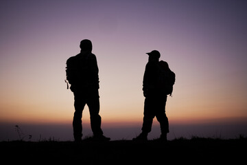 Fototapeta na wymiar Silhouette of Hiker men with backpack stay on cliff and think on the top mountain at sunset