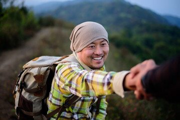 Close-up of Two male hikers helping each other climb up a mountain
