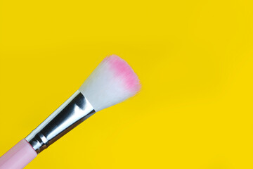 White-pink makeup brush on a yellow background.