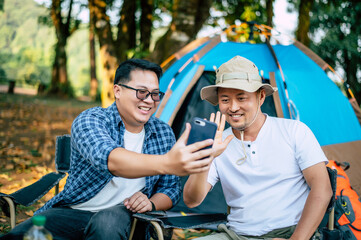 Portrait happy Asian man friends Making a video call with smartphone in camping