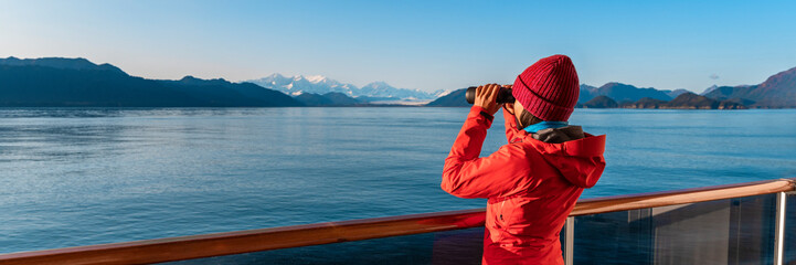 Alaska Glacier Bay cruise ship passenger looking at mountains with binoculars exploring Glacier Bay National Park. Woman on travel Inside Passage enjoying view. Panoramic vacation adventure banner. - 535683584