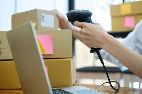 Female online business owner scanning parcel barcode tag.
