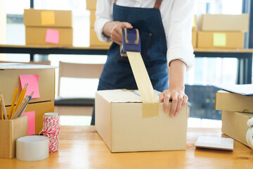 Fototapeta na wymiar Female online business owner packing order box for dispatching.