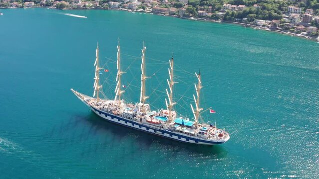 Sailing ship on the sea - old full-rigged clipper boat with five masts and square sails. Sun reflection on the blue water surface around the beautiful vintage sailboat. Kotor Montenegro