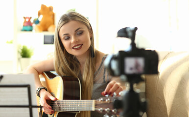 Fototapeta na wymiar Young woman plays acoustic guitar and records video clips for social networks