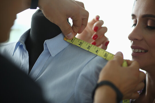 Female hands of tailor with colleague fashion designer will measure clothes on mannequin