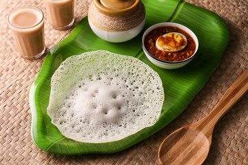 Appam, Kerala breakfast food egg curry or hot and spicy chickpea Masala and milk tea chai, Christian breakfast on dark black background. fermented rice pan cake. Top view of Indian veg food.