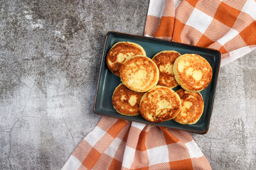 Rustic cottage cheese pancakes on a rectangular  plate on a dark background. Top view, flat lay