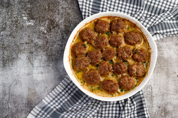 Meatballs in cheese paprika sauce in a white baking dish on a dark grey background. Top view, flat lay