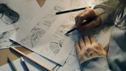 Young female artist draws sketches of comic book characters on a sheet of paper. The illustrator creates a storyboard. Storytelling concept. Video editing. - obrazy, fototapety, plakaty