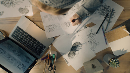 Top view of young woman drawing pencil sketches. Working on a storyboard of a comic in a design...