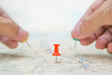 Selective focus of Red pin  and blurred hand holding a pin on map background