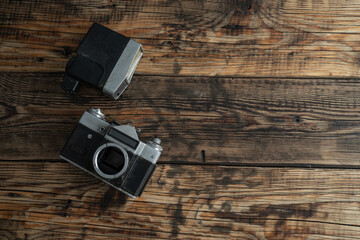 Vintage camera and retro detachable flash. Old photographic equipment composition with copy space on wooden background.