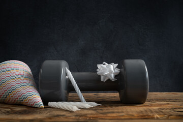 Heavy dumbbell, cone hat, bow, cake candles. Gym exercise equipment as a gift idea for birthday party. Healthy fitness lifestyle composition. Gym workout and sport training concept with copy space.