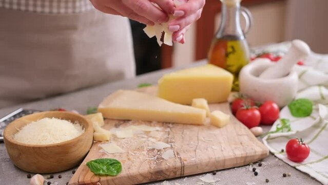 woman pours sliced flakes of parmesan hard cheese on a wooden cutting board