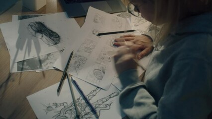 Female creative designer works on a storyboard and draws a sketches for a comic. Video editing, comics compilation, creative work concept.