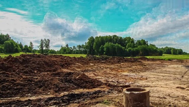 Timelapse shot of excavator loader works for formation of land on a grass field on a cloudy day.