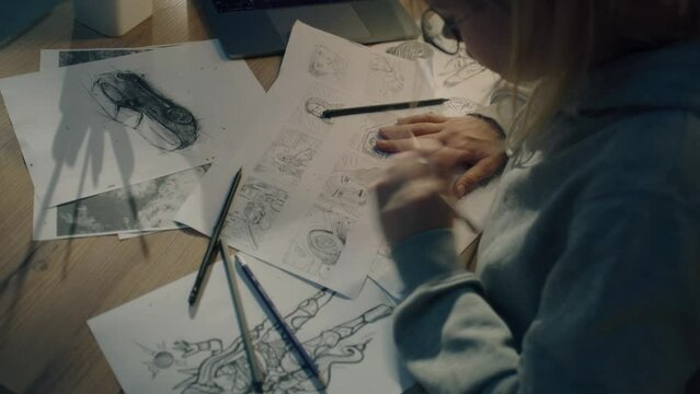Female creative designer works on a storyboard and draws a sketches for a comic. Video editing, comics compilation, creative work concept.