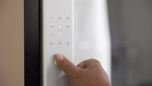 Close Up Footage of Man's hand opens the electronic digital door with a finger scan to access the home security system
