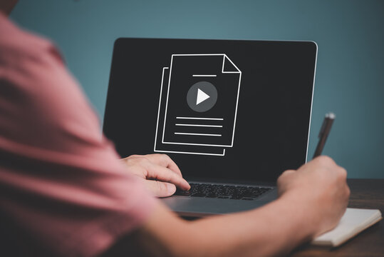 E learning concept. Casual business man studying online course via website or page on computer and writing on notebook.