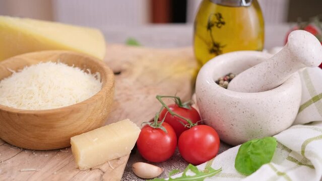Pieces of parmesan hard cheese and grated cheese in a bowl on a wooden cutting board at domestic kitchen