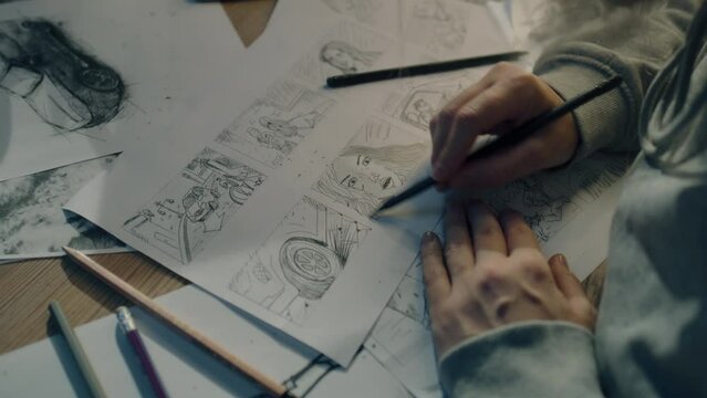 Young female artist draws sketches of comic book characters on a sheet of paper. The illustrator creates a storyboard. Storytelling concept. Video editing.